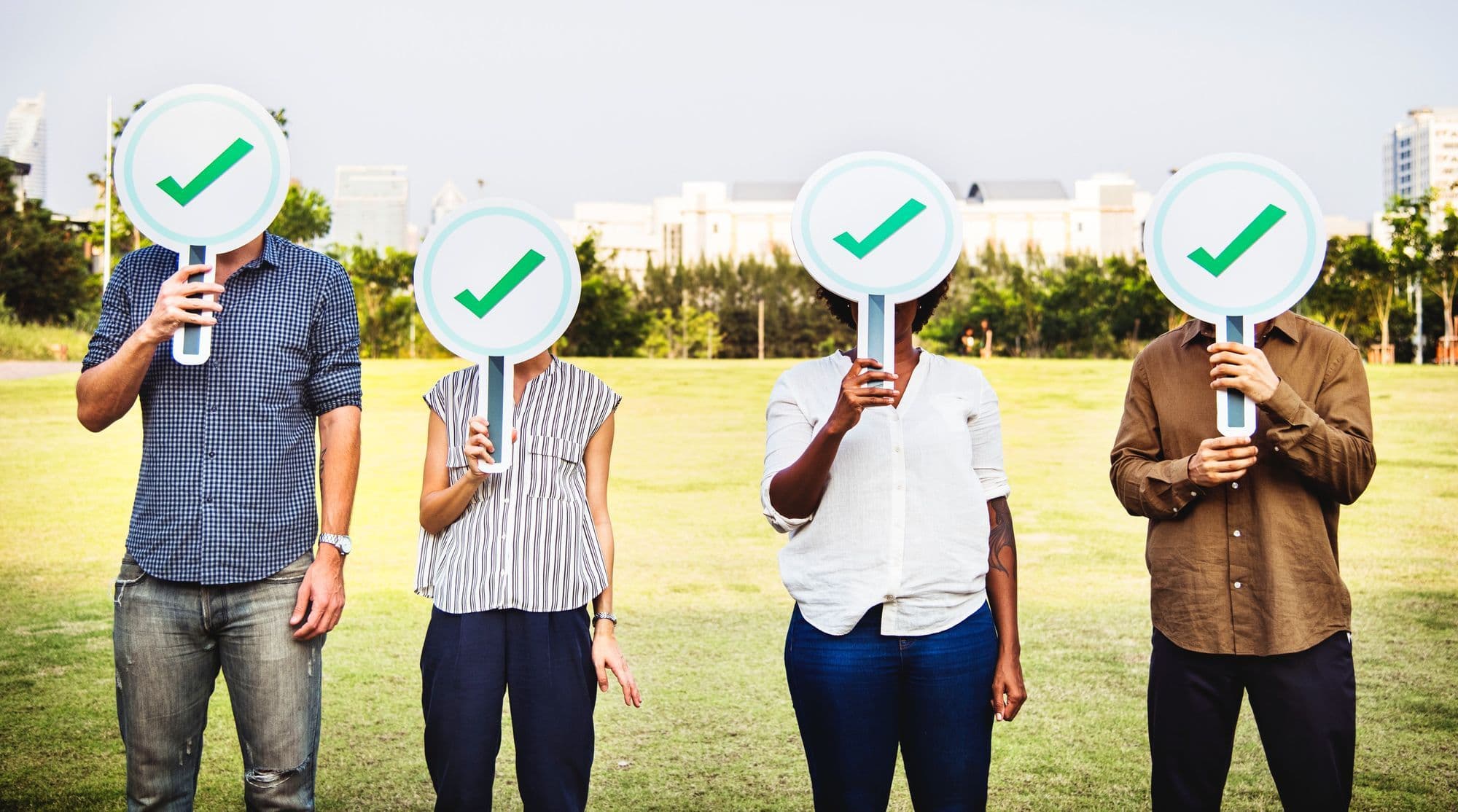 Four people holding check marks in front of their faces