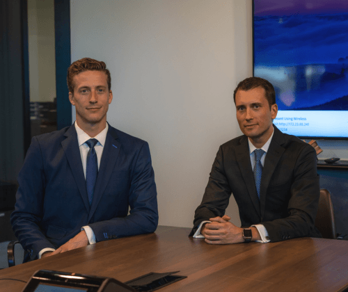 Todd Bendell and Jonathan Elliott of Optima Capital Management sitting at a table in their office