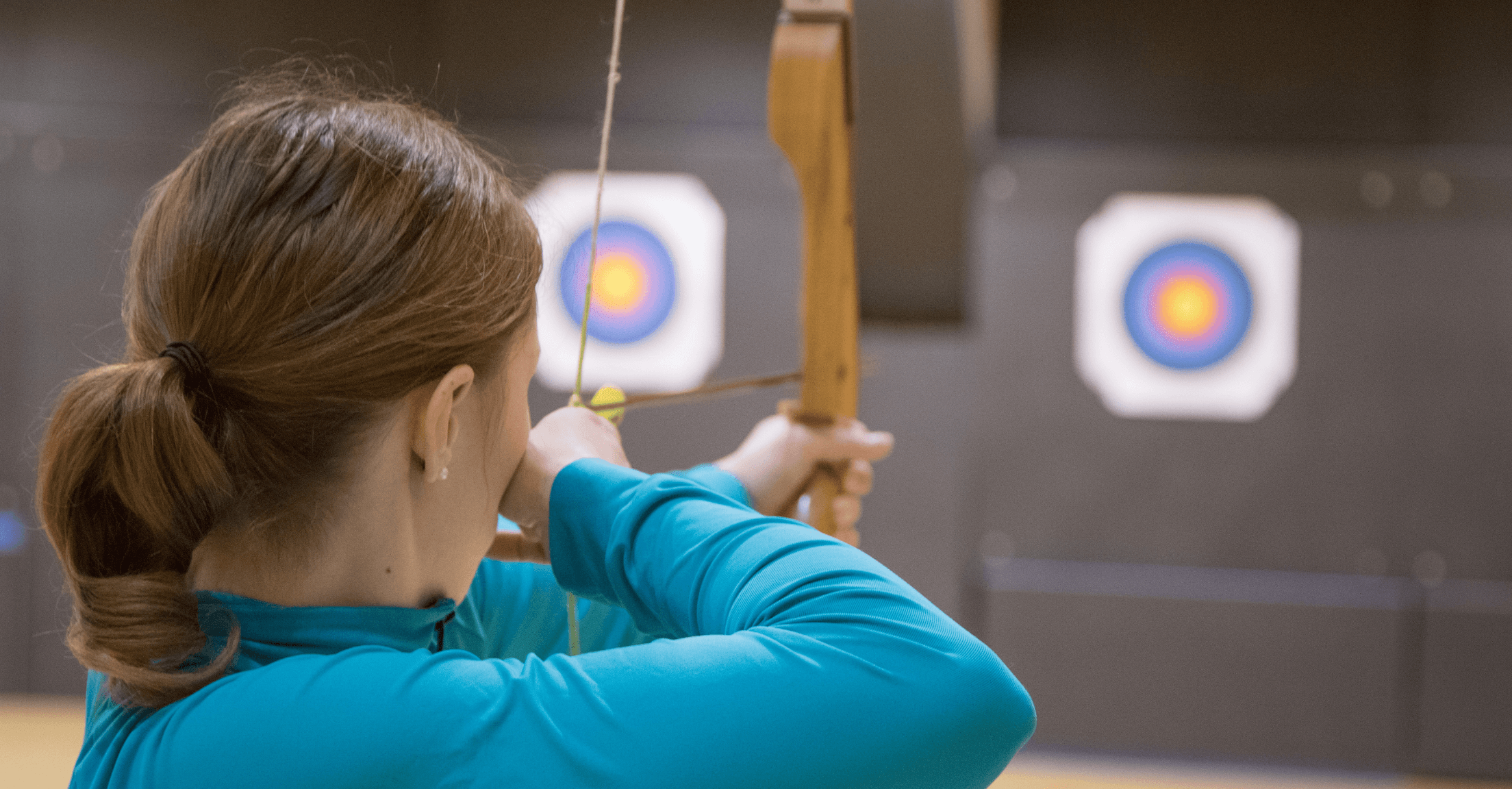 Woman shooting an arrow from a bow at targets