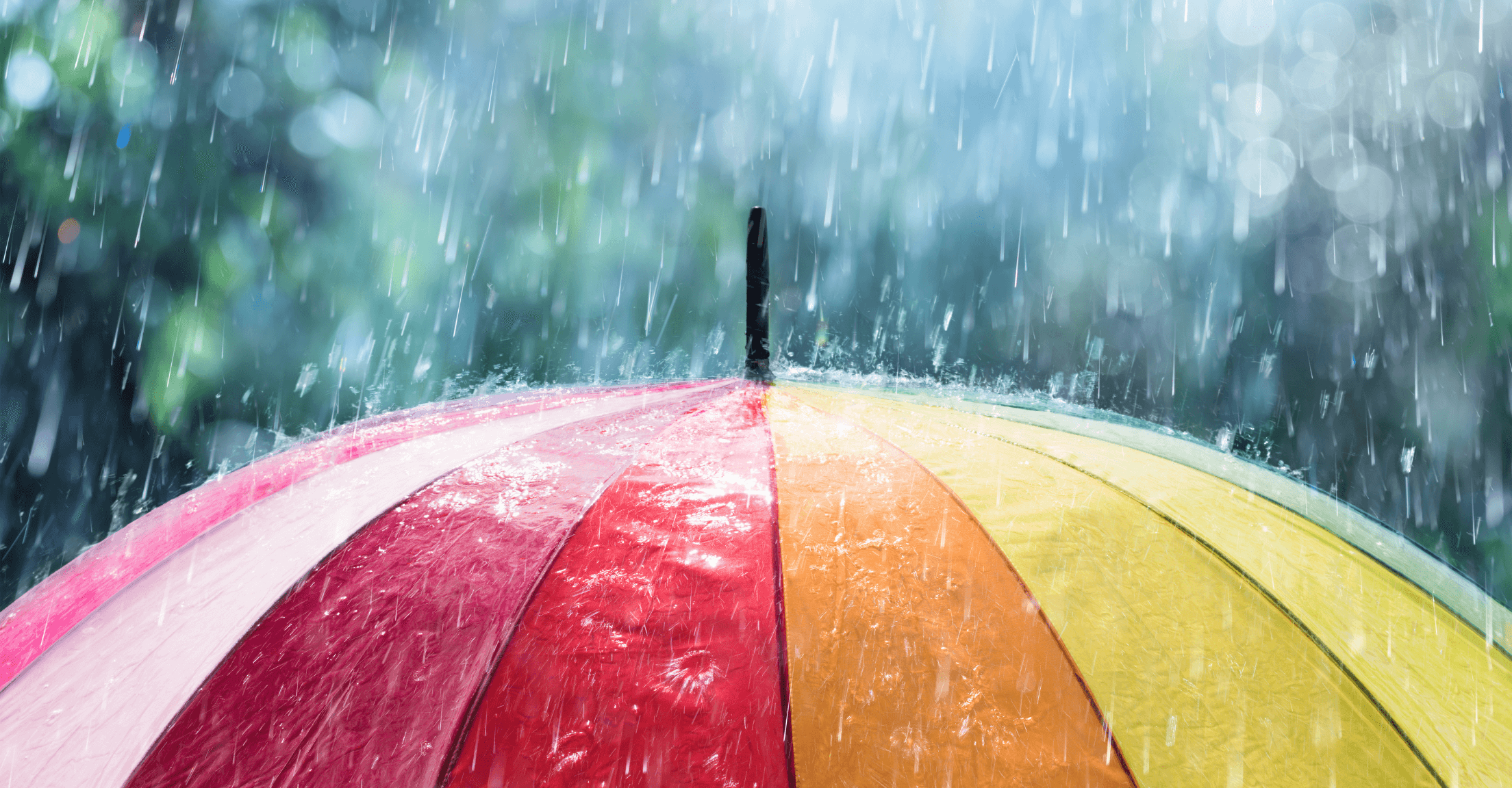 Rainbow umbrella in the rain, representing insurance coverage