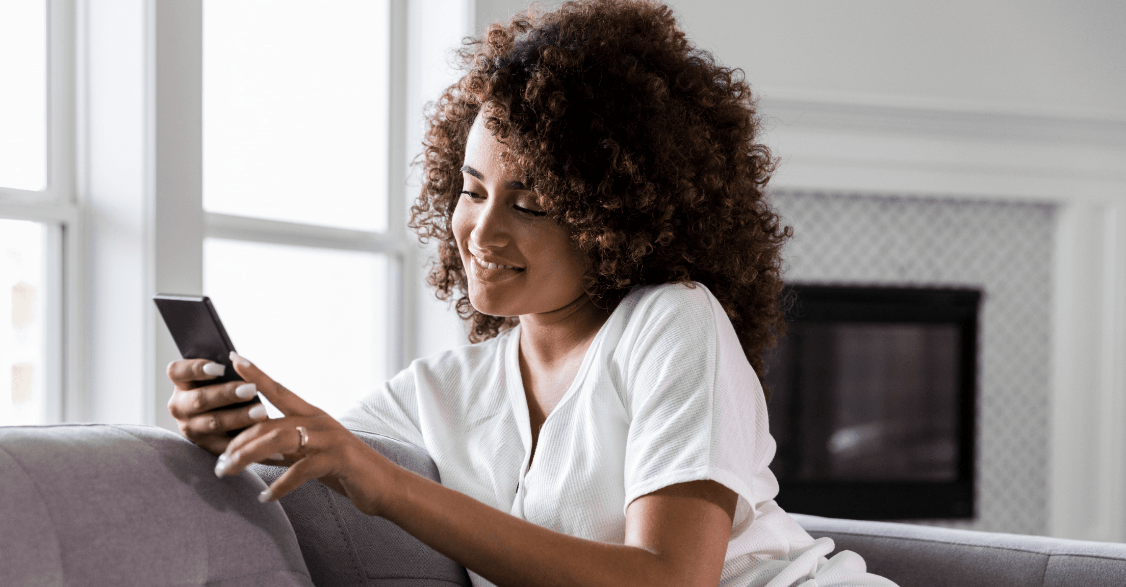 Woman sitting on a couch scrolling through her phone watching short-form videos by her financial advisor