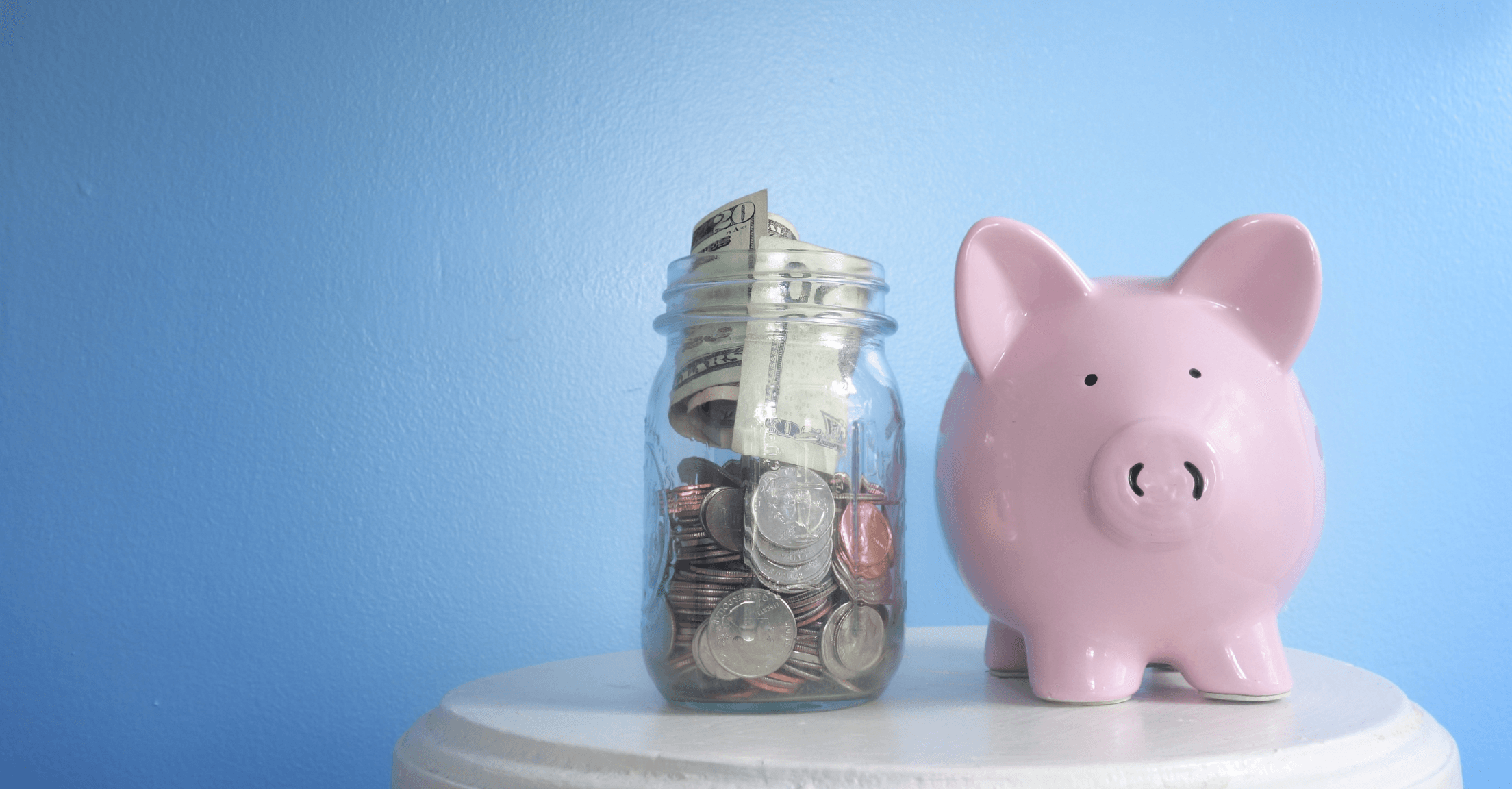 Piggy bank next to a jar full of money