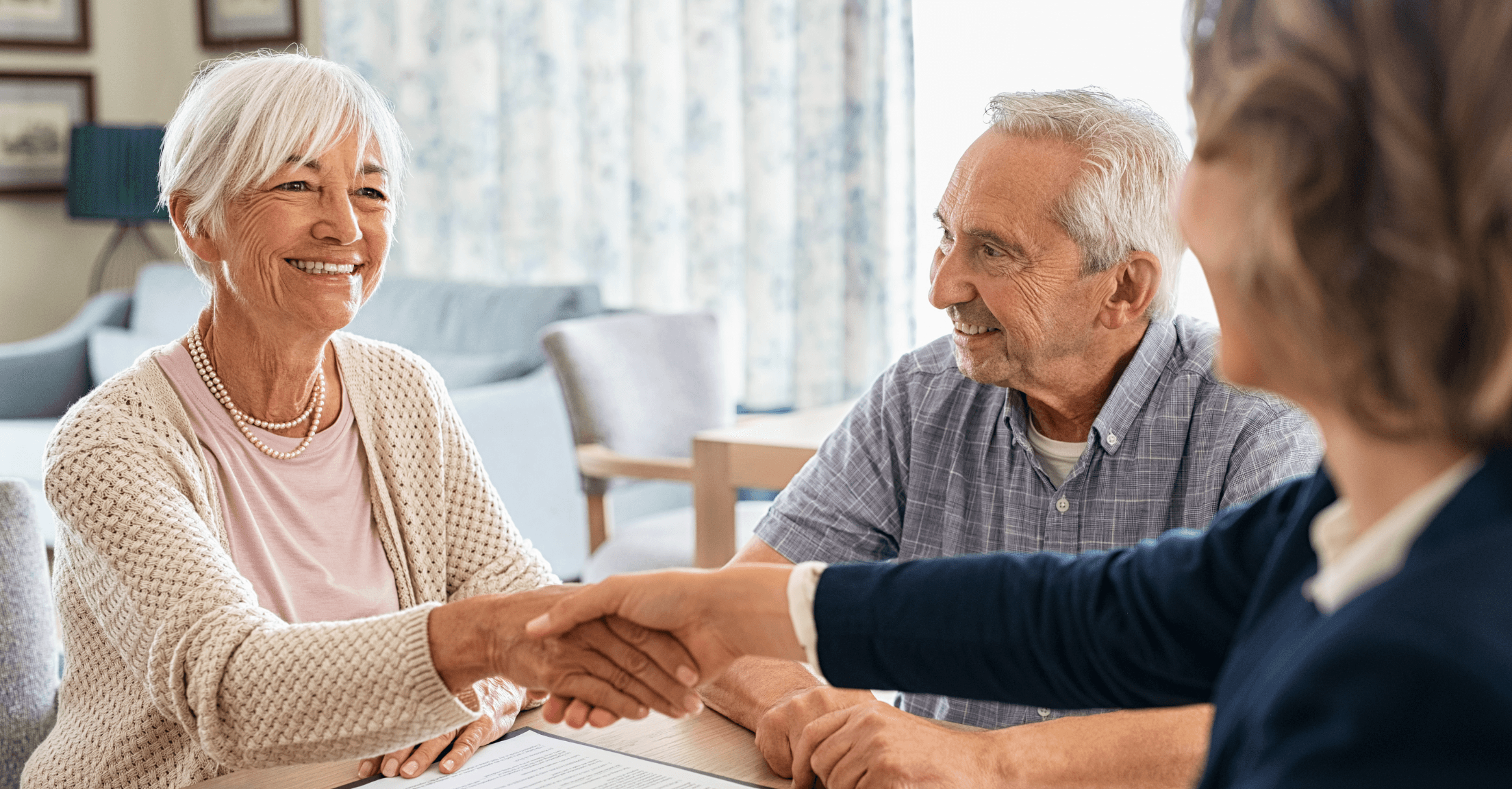 Advisor meeting with senior couple and shaking hands